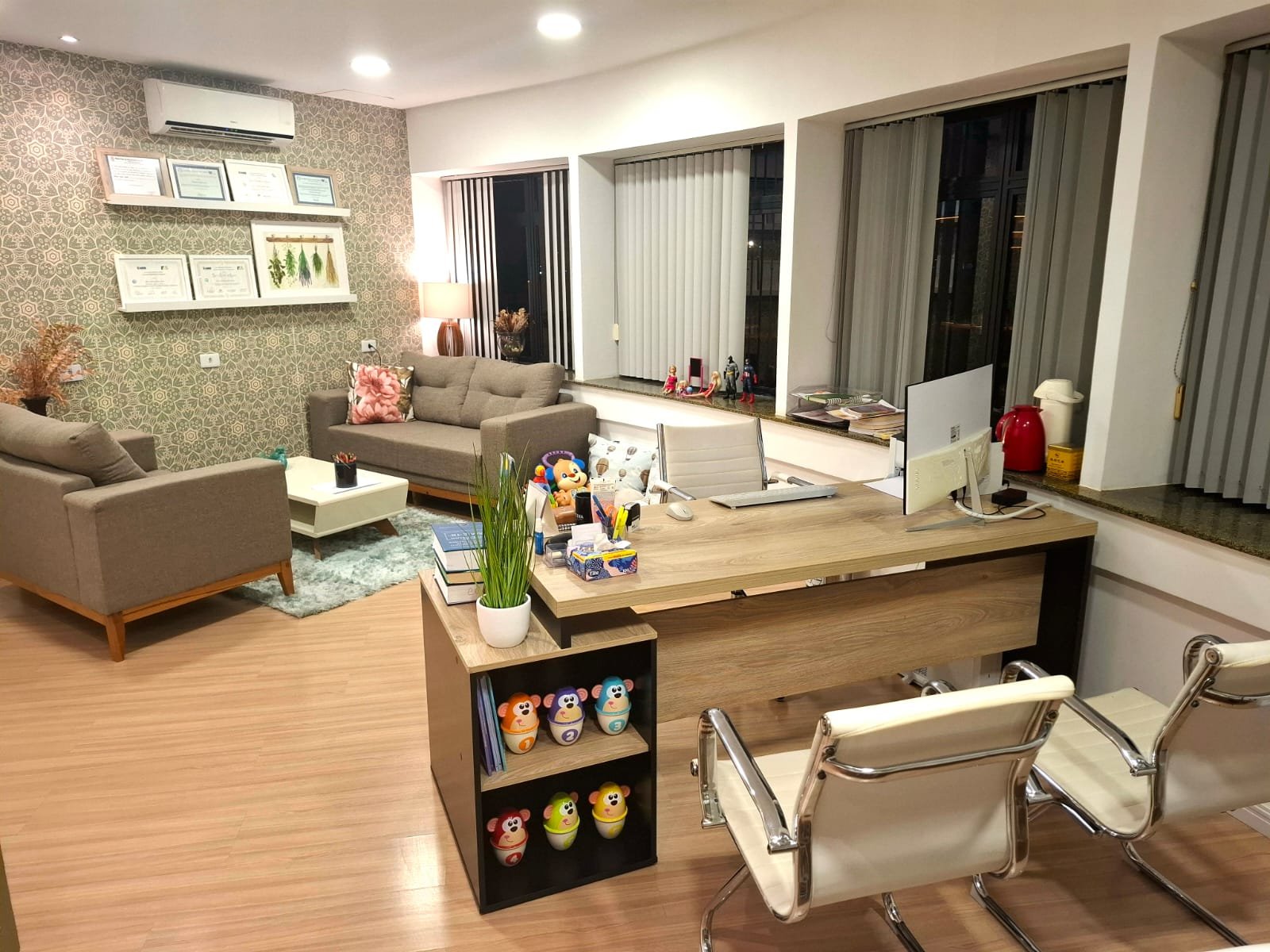 Vista panorâmica do consultório com mesa de atendimento e área de acolhimento